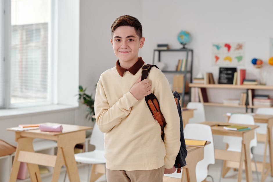 A smiling schoolboy confidently standing in a modern classroom with his backpack