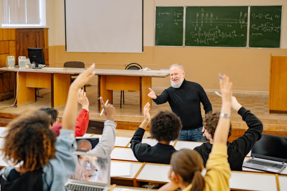 Professor engaging with students in a lively university classroom discussion as students raise hands
